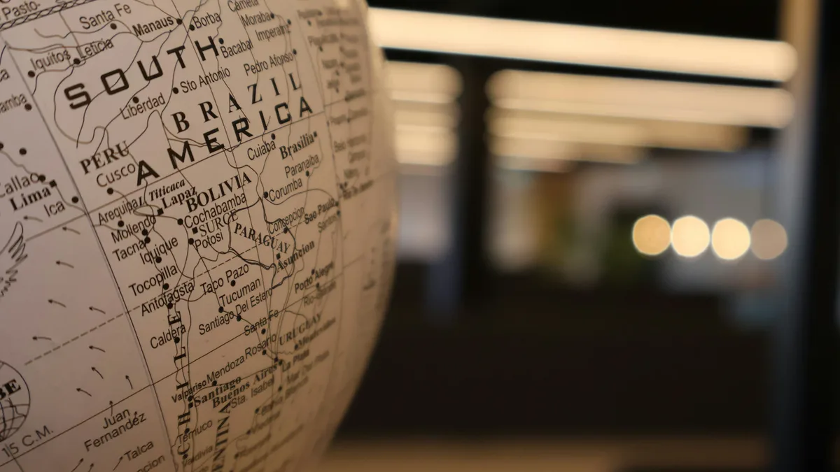 A close-up view of a globe with the South America section in focus, featuring the words "SOUTH BRAZIL AMERICA" and the names of several countries, including Brazil, Peru, and Bolivia.