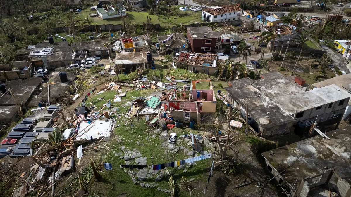 A devastated area with destroyed buildings, debris, and scattered objects, likely the aftermath of a natural disaster.
