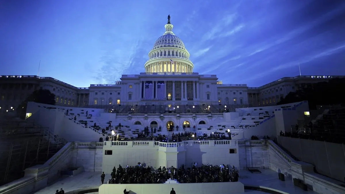 The United States Capitol building in Washington, D.C. at dusk, with a large crowd gathered in front of it.