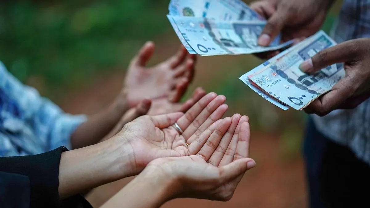 Four hands are visible, with two hands holding money and two hands open and cupped, as if receiving the money.